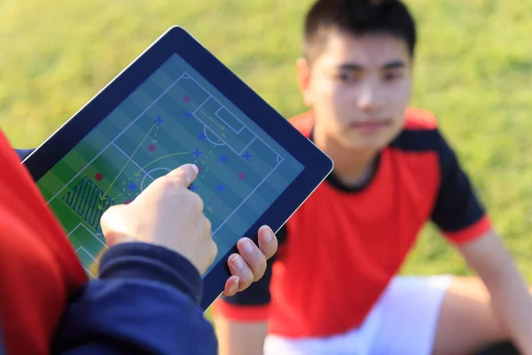 Coach training a tactic for asian teenager football player.