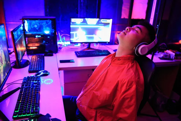 Asian gamer playing online game on PC in dark room, tired gamer sleep while playing game he away from keyboard, AFK. e-Sport Games compilation and Internet Championship.