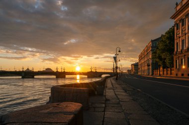 Saint Petersburg, Rusya 'da bir yaz sabahı doğan güneşin ilk ışıklarıyla Neva Nehri üzerindeki Saray Duvarı ve Üçlemeci Köprüsü' nün suyuna inişin görüntüsü