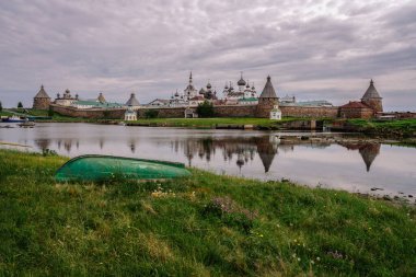Beyaz Deniz Körfezi kıyısındaki Solovetsky Manastırı ve bulutlu bir yaz gününde önplandaki eski tekne, Solovetsky Adası, Arkhangelsk Bölgesi, Rusya
