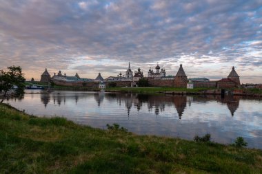 Beyaz Deniz Koyu 'nun kıyısındaki Solovetsky Manastırı' nın görüntüsü, günbatımı gökyüzünün arka planında yansıması bulutlarla, Solovetsky Adası, Arkhangelsk Bölgesi, Rusya