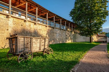 Izborsk Kalesi 'nin (XIV-XVII yüzyıllar) kale duvarının savaş rotası ve güneşli bir yaz akşamında bölgede eski bir geleneksel köy arabası. Stary Izborsk, Pskov bölgesi