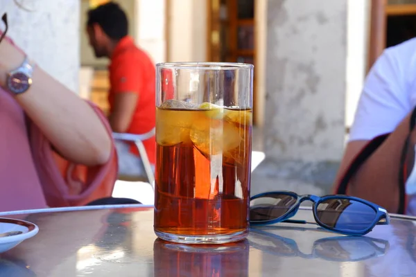 Glass of ice tea with sun glasses and people