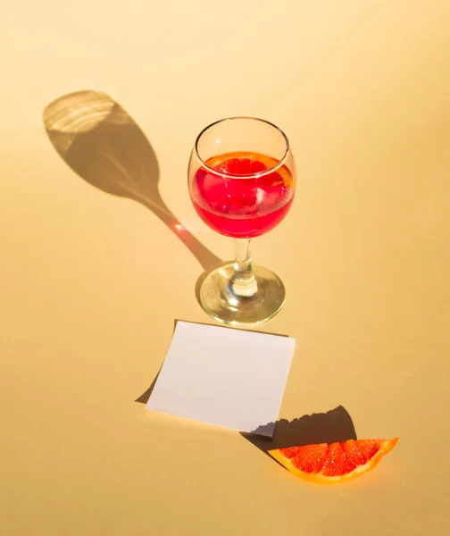 Bardakta taze sıkılmış greyfurt suyu ve kopyalanmış bir parça narenciye. Şampanya arka planı ve şarap kadehinin gölgesi. Yaratıcı asgari kavram.