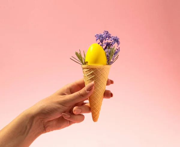 Sarı yumurtalı dondurma külahı ve pembe arka planda bahar çiçeği sümbülü. Retro estetik. Asgari Paskalya Konsepti 2021. 