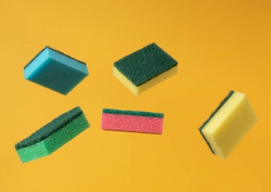 Sarı arka planda bulaşık süngeri. Minimum denge bileşimi. Ev temizleme kavramı.