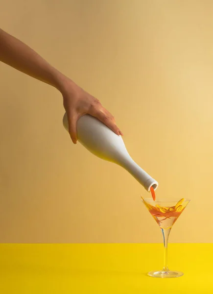 Martini bardağına çiçek yaprakları döken şişe. Parti yaz konsepti.