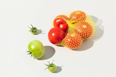 Beyaz arka planda yeşil olgunlaşmamış domates ve kırmızı olgun domatesler. En az gıda konsepti. 