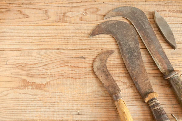 Three dated and used billhooks on wooden background — Stok fotoğraf