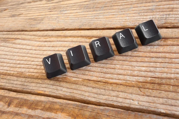 "VIRAL "wrote with keyboard keys on wooden background — стоковое фото