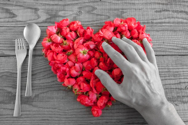 Coeur en roses rouges en fond de bois, recouvert d'une main Images De Stock Libres De Droits
