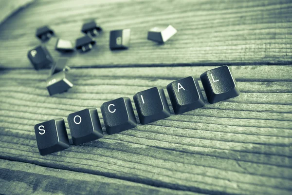 "social "wrote with keyboard keys on wooden background, green vi — стоковое фото