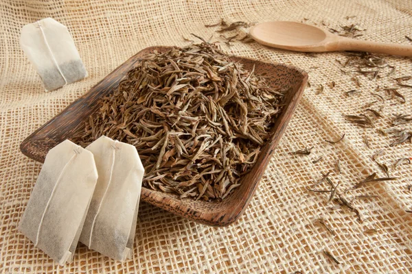 Hojas de té secas en una taza de madera, estilo país — Foto de Stock