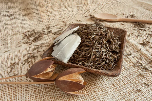 Hojas de té secas en una taza de madera, estilo país — Foto de Stock