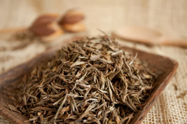 Hojas de té secas en una taza de madera, estilo país — Foto de Stock