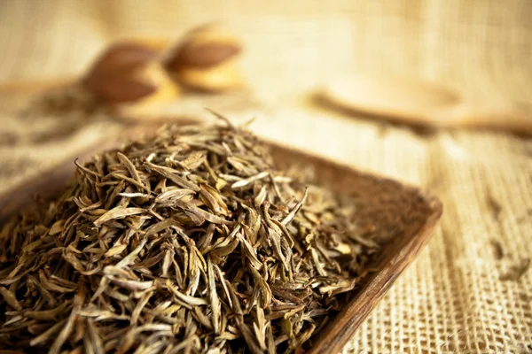 Hojas de té secas en una taza de madera, estilo país — Foto de Stock