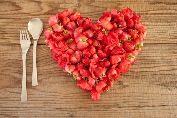 Coração feito de rosas vermelhas em fundo de madeira — Fotografia de Stock