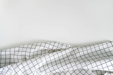 Alt kısımda beyaz arkaplan buruşmuş beyaz kareli mutfak peçetesi dokusu. Masa modern tarz minimalizmi kırsallaştırıyor. Bir yazı için arkaplan. Örtüler ve katlar. Masa örtüsü.