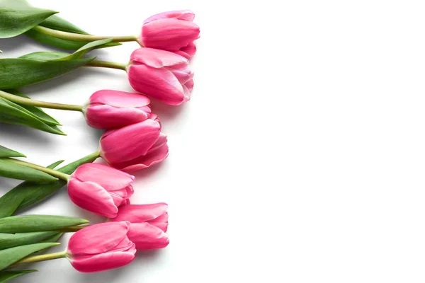 Beyaz arka planda sol tarafta pembe laleler var.