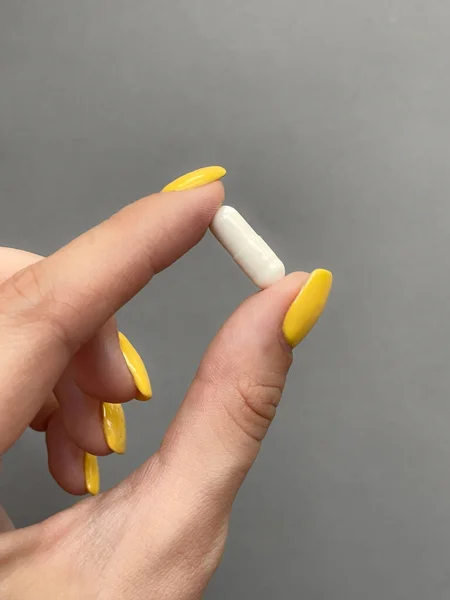 Kız elinde beyaz bir hap tutuyor..