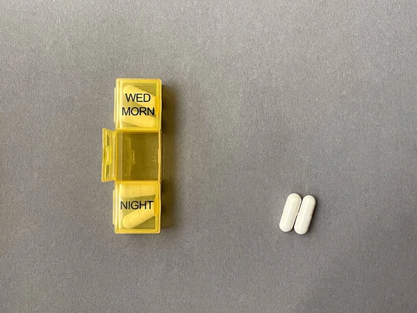 Hap organizatörüne hap verin. Gri arka planda yatan iki hap..