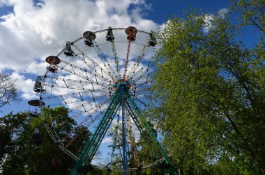 Arka planda yeni bir huş ağacı olan eski renkli bir dönme dolap.