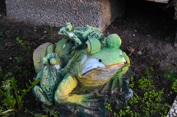 A garden figure depicting a frog with two small frogs sitting on its back.