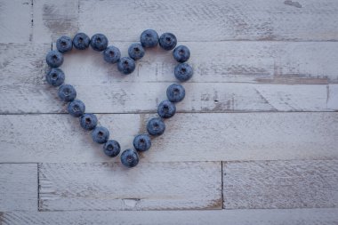 Böğürtlen kompozisyonu kalp şeklinde beyaz ahşap arka planda aşk meyveleri