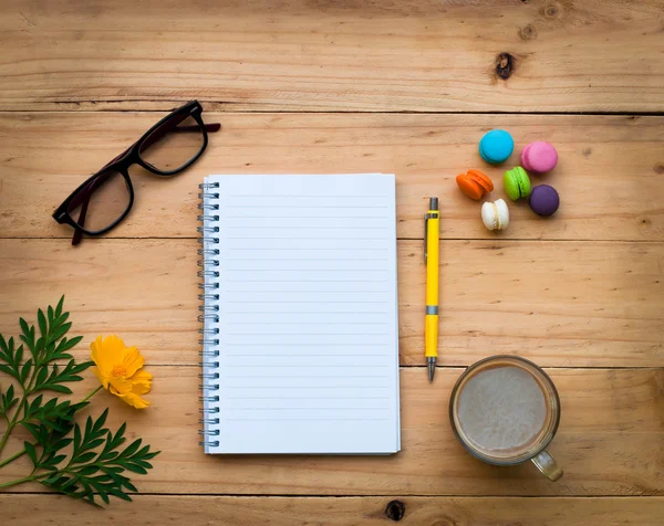 Cuaderno en blanco y una pluma amarilla con café caliente y dulce colorido en la mesa de madera en tono cálido . — Foto de Stock