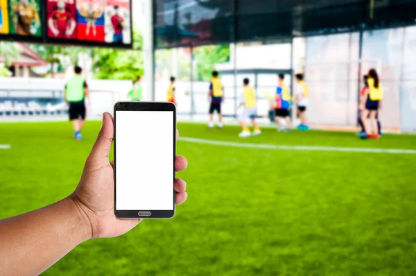 La mano del hombre sostiene el teléfono móvil sobre el atleta borroso son playi — Foto de Stock