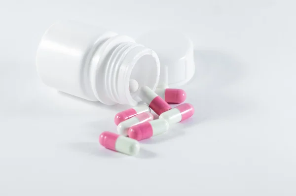Beyaz plastik şişeden dökülüp beyaz-pembe hap