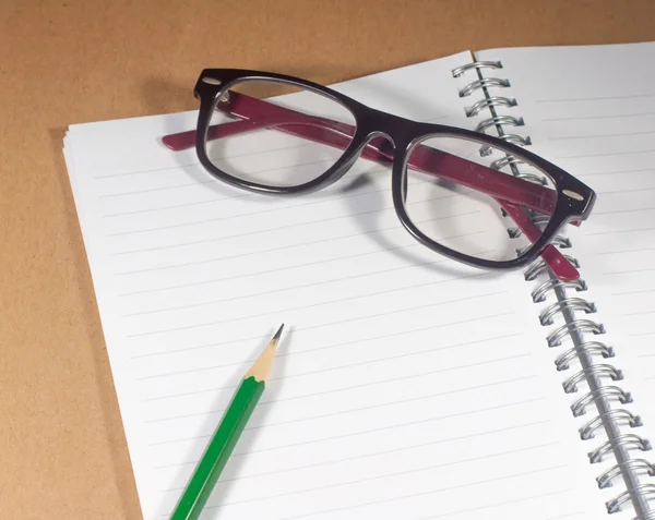 Öppen tom anteckningsbok med grön penna, glasögon och fodrad sida — Stockfoto