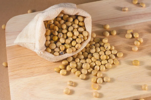 木材の背景に袋に大豆や黄色の豆 — ストック写真