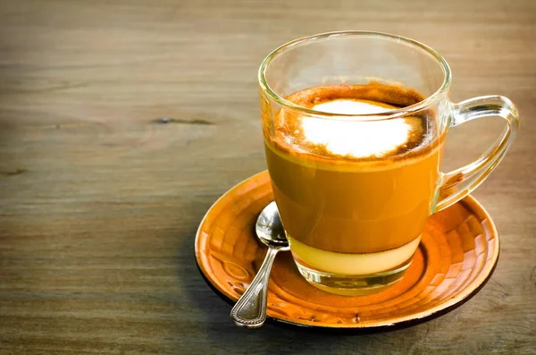 Чашка горячего карамельного кофе в прозрачной чашке на деревянном фоне — стоковое фото