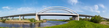Almanya 'nın kuzeyinde Schleswig-Holstein eyâletinde, Itzehoe yakınlarındaki Str Nehri' ni kapsayan modern karayolu kemeri açık mavi gökyüzünün altında..