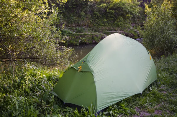 Green tent in the forest near river — Stock Photo, Image