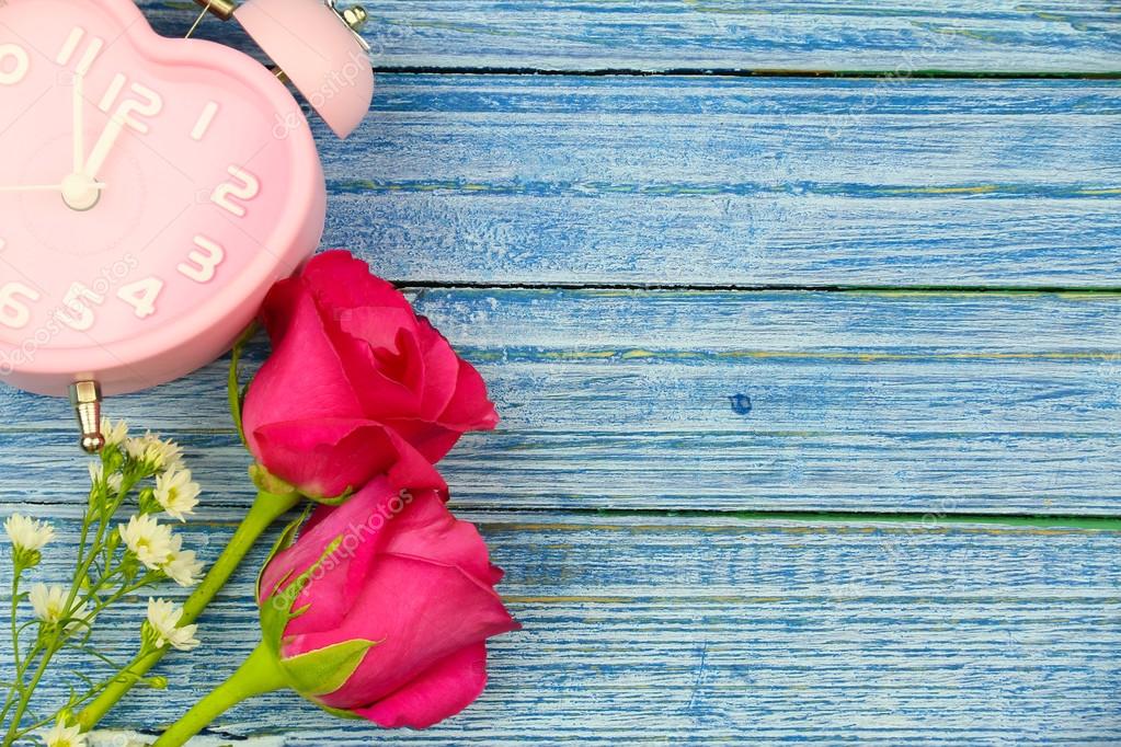 Time of love. pink rose and pink heart watch on the blue wooden background with copy space for valentine day.