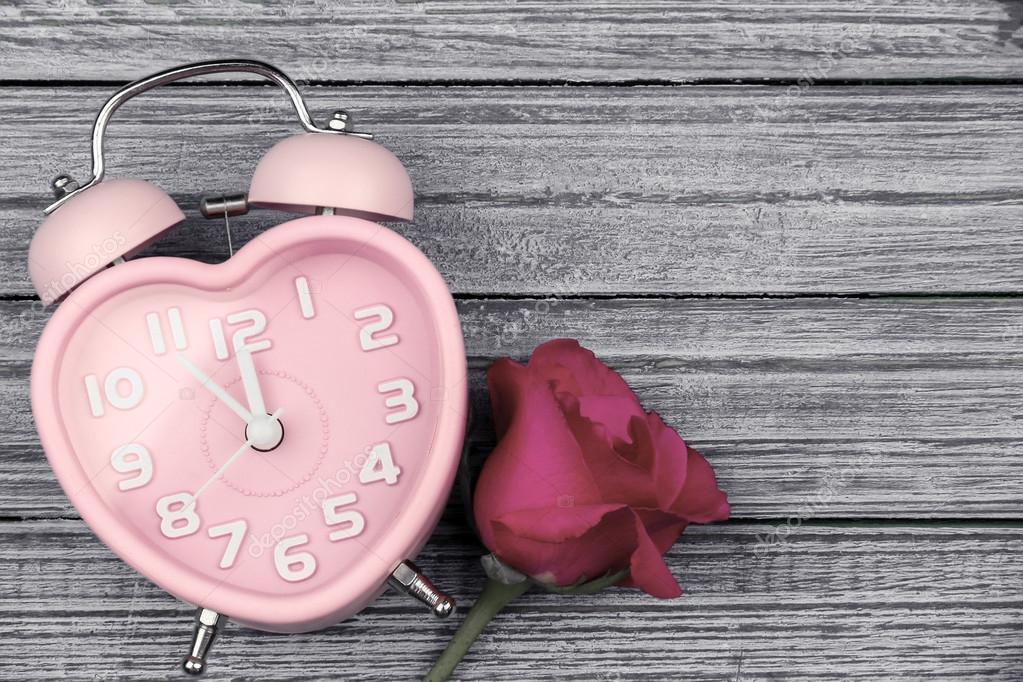 Time of love. pink rose and pink heart watch on the blue wooden background with copy space for valentine day.