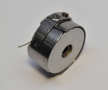 Beyaz arkaplandaki bobbin kutusuna kahverengi iplikli paslanmaz bobbin..