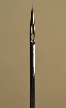 Dikiş iğnesinin gözüne yakın çekim. Bunlar endüstriyel aşırı kilitlenme makineleri için yuvarlak şiş iğneleri..