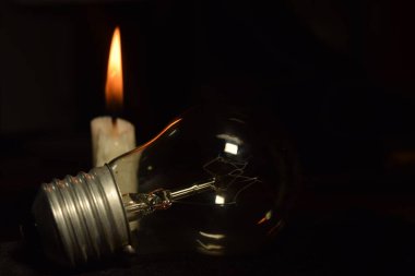 a lamp and one candle blur burning in the dark background. power outage. blackout begin. clipart