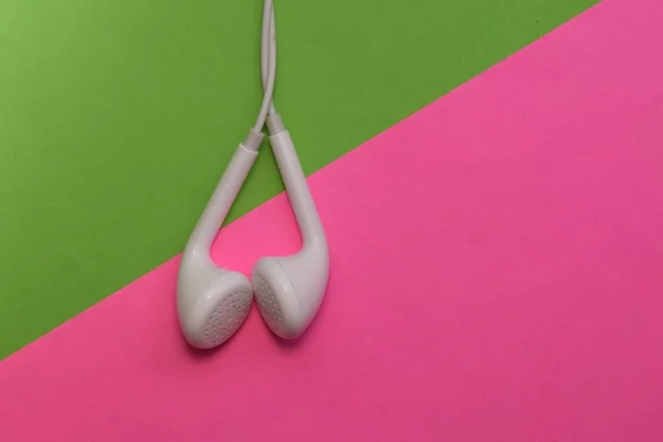 White earphones on green and pink background.