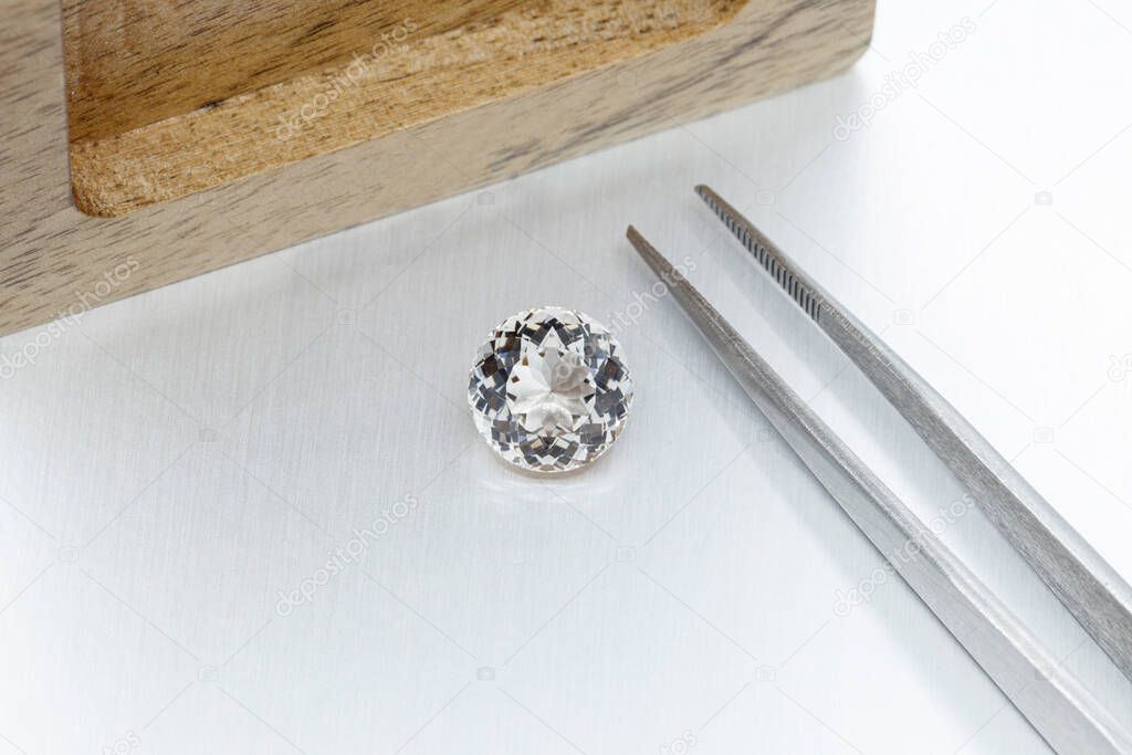 macro mineral faceted stone Morganite with tweezers on a gray background close-up