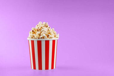 Pembe arka planda klasik kırmızı çizgili patlamış mısır karton bardak.