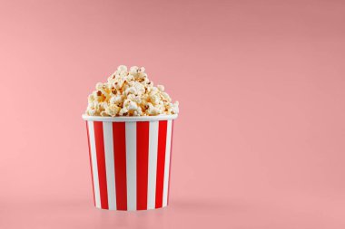 Kırmızı arka planda klasik kırmızı çizgili patlamış mısır karton bardak.