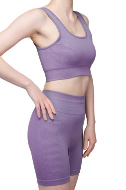 Formda bir kadının sırtından atölye çekiminde, gri çatallı, pürüzsüz spor şortu ve uyumlu spor sutyeni sergileniyor. Kumaş desenli bir örgü. Beyaz arka planda izole edilmiş. Spor giyim, spor giyim ve fitness programları için ideal.