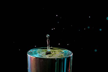 Su damlası düşüyor, makro sıçrama. Doğal ve karanlık bir arkaplanda yakın plan.