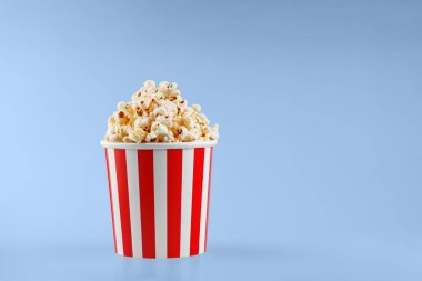 Mavi arka planda klasik kırmızı çizgili patlamış mısır karton bardak.