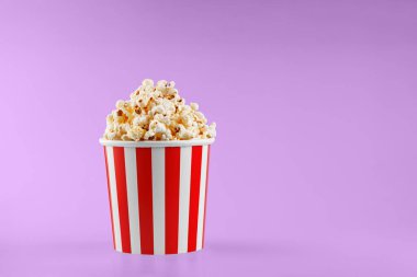 Pembe arka planda klasik kırmızı çizgili patlamış mısır karton bardak.