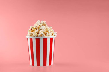 Kırmızı arka planda klasik kırmızı çizgili patlamış mısır karton bardak.